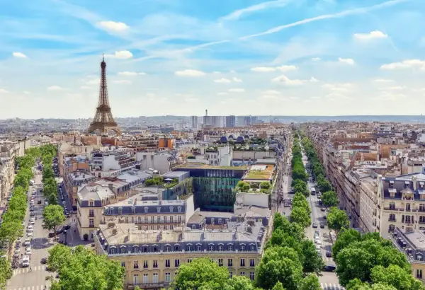 Vy över Paris med Eiffeltornet i fjärran. En grönskande allé leder mot stadens centrum, där takåsarna vittnar om stadens rika historia och många museum.