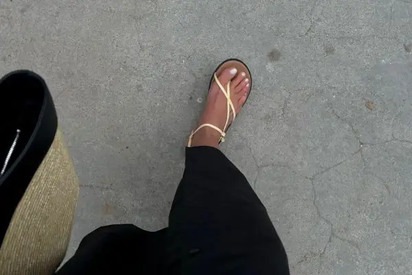 En fot i ljusgula sandaler från Vero Moda skor, med svart kjol och en stråväska.