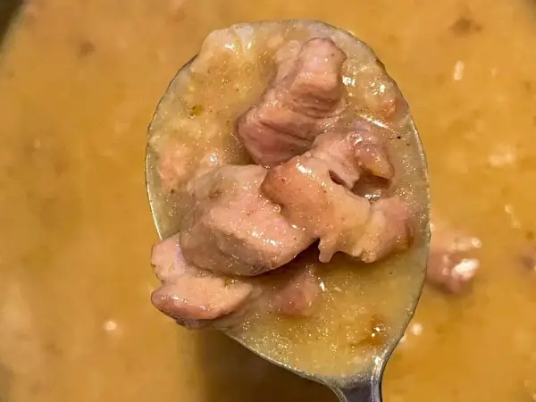 Łyżka pełna soczystej karkówki w sosie, gotowa do podania. Aromatyczne danie, które rozpływa się w ustach.