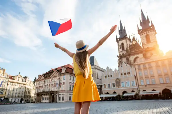 Kobieta z flagą Czech na Rynku Staromiejskim w Pradze. Słowa po czesku, radość podróżowania.