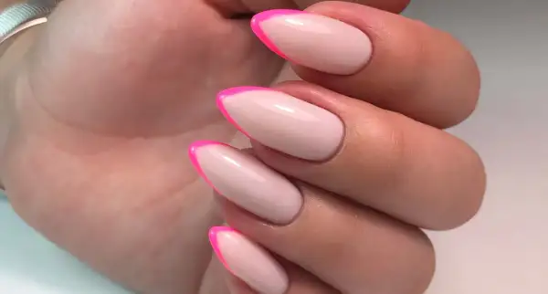 Manucure française tendance avec des pointes rose vif sur une base nude. Un look audacieux et chic.