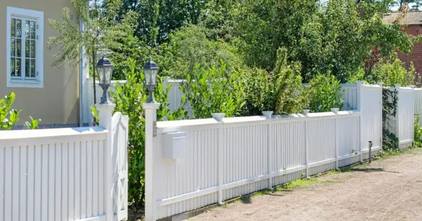 Vitt staket med brevlåda och lampor. En vacker trädgård att bygga staket i.