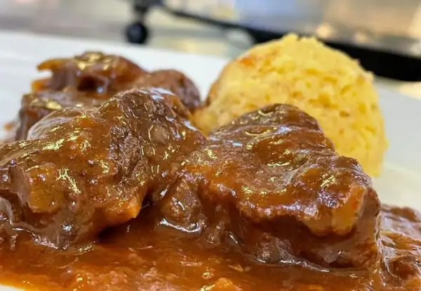 Un saporito gulash trentino, con carne tenera in salsa ricca e una porzione di polenta dorata.