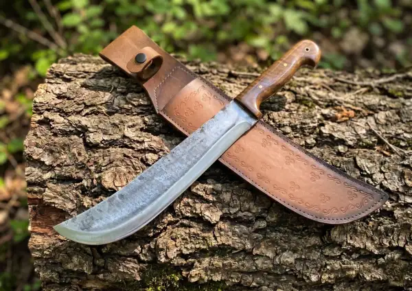 Machete de hoja ancha y mango de madera, con funda de cuero grabada. Descubre su machete precio.
