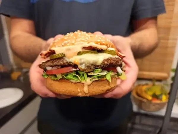 Idealny burger: soczysta wołowina, ser, chrupiąca sałata, pomidor, ogórek i sos. Oto jak składać burgera krok po kroku.