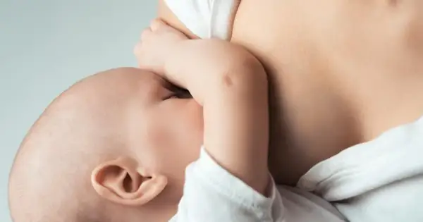 Maluszek ssie pierś, co jest naturalnym sposobem na pobudzenie laktacji. Bliskość mamy i dziecka.