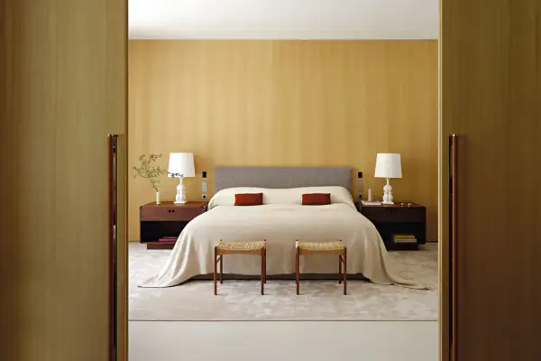 Modernes Schlafzimmer mit Holzakzenten, einem bequemen Bett und zwei Hockern. Tolle schlafzimmer ideen modern für ein stilvolles Zuhause.