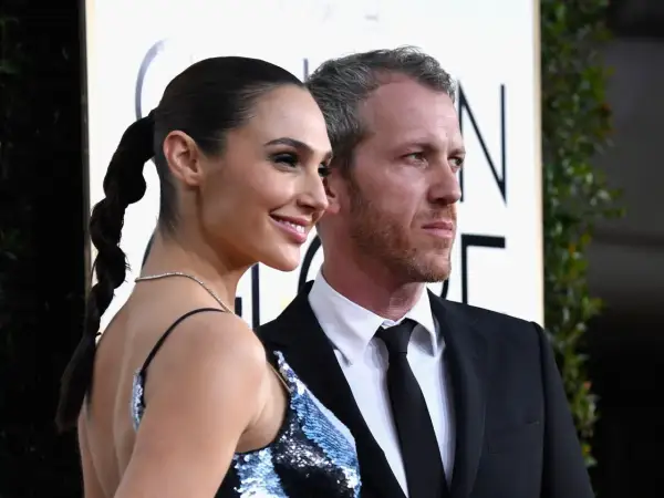 Yaron Varsano y su esposa, Gal Gadot, posan sonrientes en la alfombra dorada.