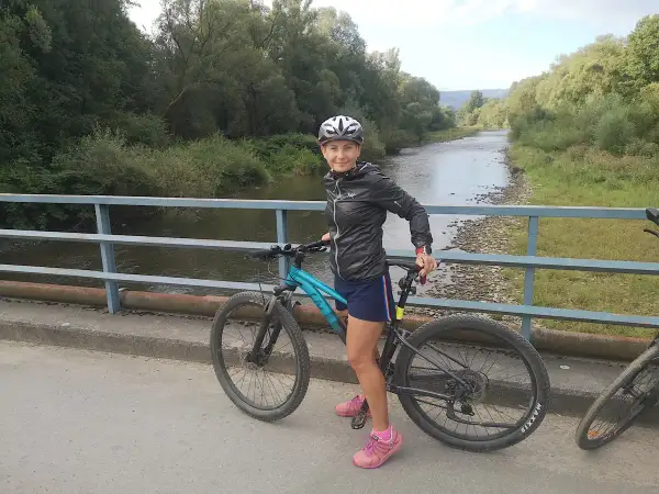 Kobieta na rowerze na moście, gotowa do odkrywania malowniczych velo tras rowerowych wzdłuż rzeki.