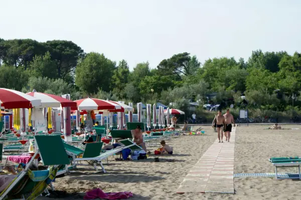 Plaża w Caorle, Santa Margherita. Rzędy parasoli i leżaków, ludzie odpoczywają. Idealne miejsce na camping.
