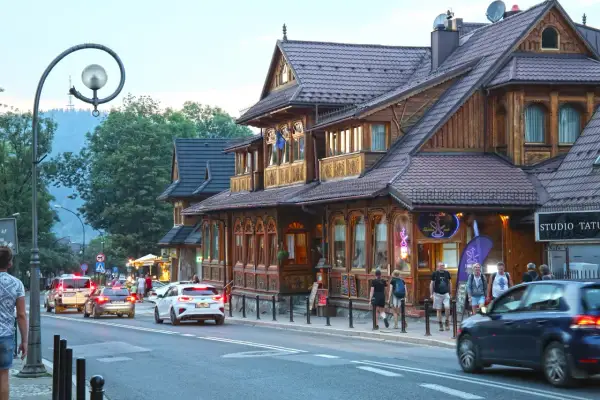Spacer po tętniącym życiem białka tatrzańska centrum. Drewniane budynki, ruch uliczny i ludzie tworzą malowniczy widok.