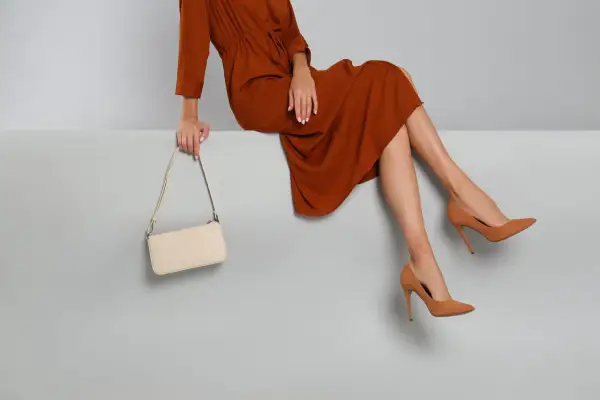 Elegant braunes Kleid, cremefarbene Tasche und braune Pumps – so zieht man in die Oper.