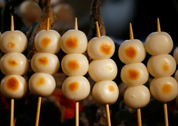 Proste japońskie dania: słodkie kluseczki mochi na patyczkach, lekko przypieczone.