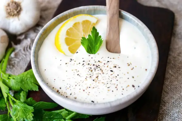 Cremiger knoblauch dip mit Zitrone und Petersilie, bestreut mit Pfeffer. Perfekt zum Dippen!