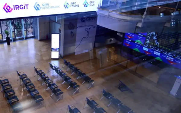 Sala konferencyjna z rzędami krzeseł, na ekranach widoczne dane giełdowe, w tym knf rejestr pozycji krótkich.