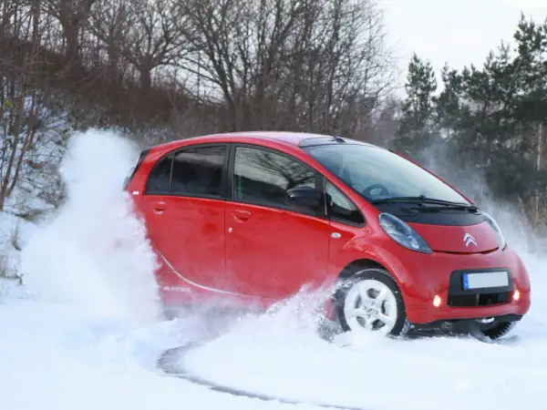 Röd Citroën C-Zero kör genom snö, skapar en stor snövirvel.