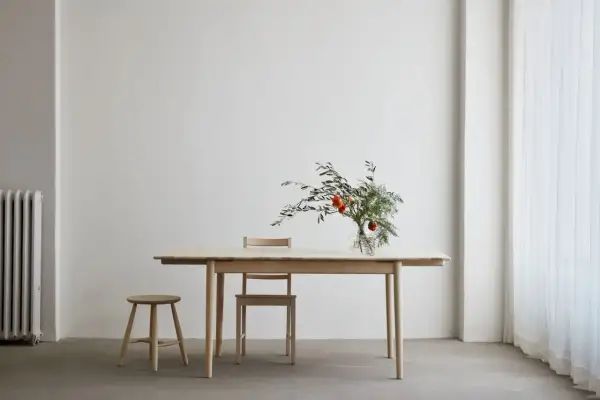 Ett ljust såpa ekbord med en vas med blommor och en pall.