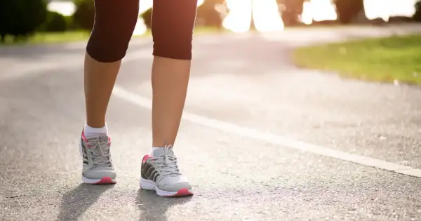 Kobieta w sportowych butach biegnie po asfaltowej ścieżce. Czy bieganie odchudza? Tak, regularny wysiłek pomaga spalić kalorie i osiągnąć wymarzoną sylwetkę.
