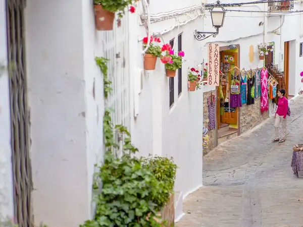 Calle estrecha en el centro de Almería, con casas blancas, flores y una tienda de ropa.