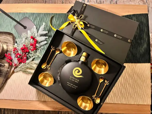 Elegante confezione regalo con olio d'oliva extra vergine, coppette e cucchiaini dorati. Regalare olio d'oliva ha un significato di benessere e cura.