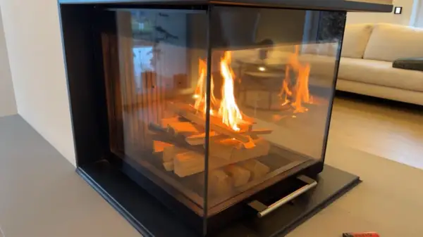 Ein moderner Kamin mit brennendem Holz. Die Flammen tanzen und geben ein warmes Licht ab, das die Frage aufwirft, wie lange brennt ein holzscheit wohl?
