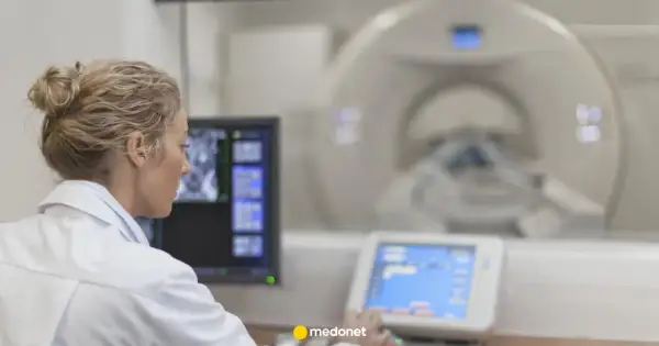 Lekarka w białym fartuchu analizuje obraz z rezonansu magnetycznego na monitorze.
