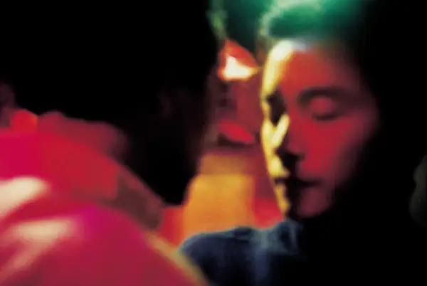Un bacio intenso, un momento di passione tra due persone. L'atmosfera è carica di emozione, quasi come un sogno, un ricordo sfocato di Wing Shya.
