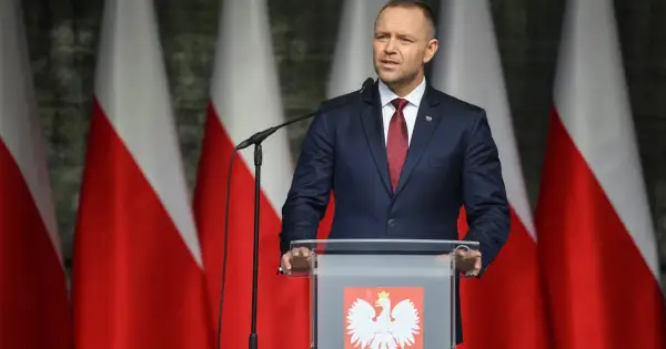 Mężczyzna w garniturze przemawia na tle flag Polski. Może właśnie użył swojego prawa weta.