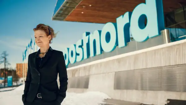 Annemarie Gardshol står framför Postnords logotyp en solig vinterdag.