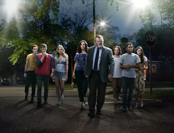 En grupp människor, inklusive rollistan i Mr. Mercedes, går mot kameran på en mörk gata under en gatlykta.