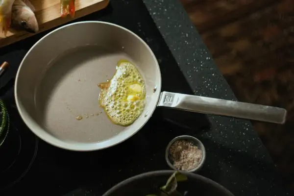 Butter schmilzt in einer beschichteten Pfanne, bereit für das Braten von Fisch. Die Pfanne wird nach dem Kochen einfach zu reinigen sein.