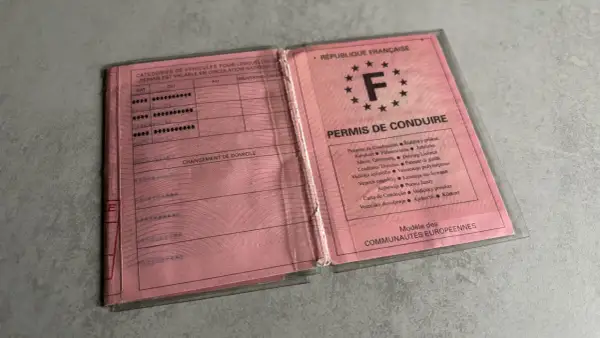 Un ancien permis de conduire français, rose, ouvert, montrant les catégories de véhicules et les mentions.