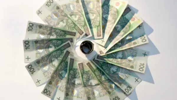 Złote banknoty o nominale 100 zł ułożone w okrąg, z pierścieniem pośrodku. Oficjalny sposób na oszczędzanie.