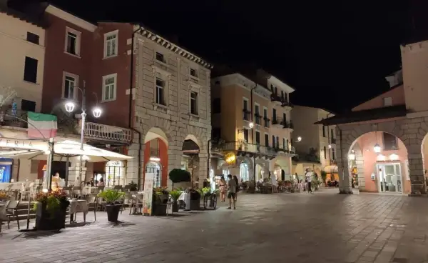 Serata nel centro storico Desenzano del Garda, con locali illuminati e tavolini all'aperto.