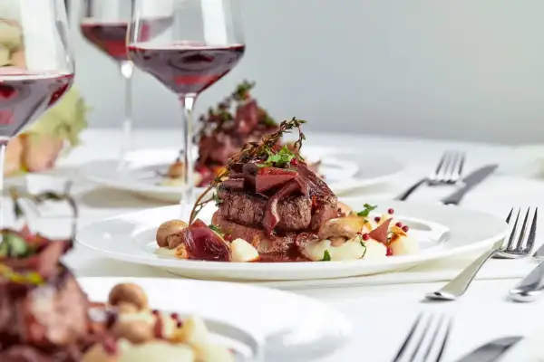 Eleganckie danie z wołowiny z puree i grzybami, podane z czerwonym winem. Zastanawiasz się, ile za talerzyk na wesele?