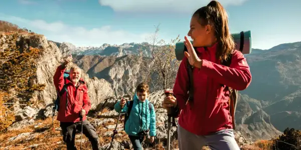 Familia disfrutando de la vista en la montaña, con ropa adecuada para la montaña y equipo de senderismo.