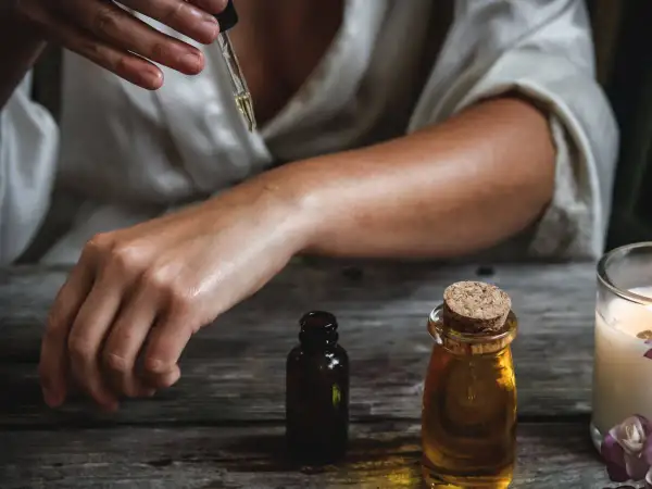 Una persona aplica aceite esencial en su brazo, mostrando cómo usar aceites esenciales para el cuidado de la piel.