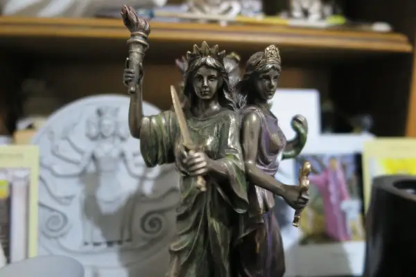 Figurka Hekate z pochodnią i mieczem, symbolizująca jej moc nad magią i przejściami.