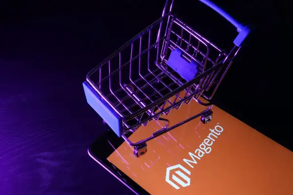 Miniaturowy wózek na zakupy na ekranie z logo Magento, symbolizującym potęgę ecommerce.