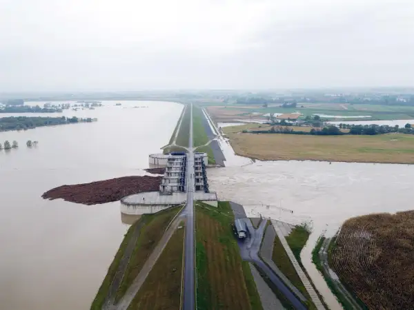 Ogromna tama i budowle hydrotechniczne walczą z żywiołem. Woda sięga pól uprawnych, a w oddali widać zalane tereny. To obraz powodzi błyskawicznej.