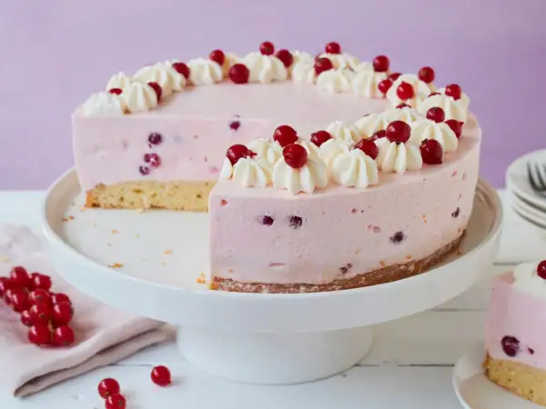 Eine köstliche Johannisbeertorte mit Joghurt, verziert mit Sahnetuffs und frischen roten Johannisbeeren.