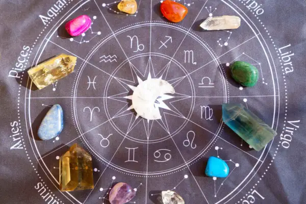 Kamienie szlachetne, w tym lapis lazuli, ułożone wokół znaku zodiaku na czarnym tle.