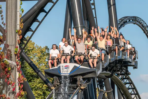 Ludzie na kolejce górskiej Hyperion w Energylandii, z rękami w górze, krzyczący z ekscytacji.
