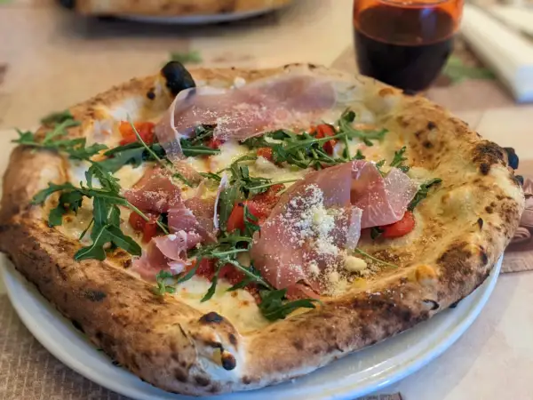 Eine köstliche Pizza mit Prosciutto, Rucola und Tomaten, die aussieht wie die beste Pizza Neapels.