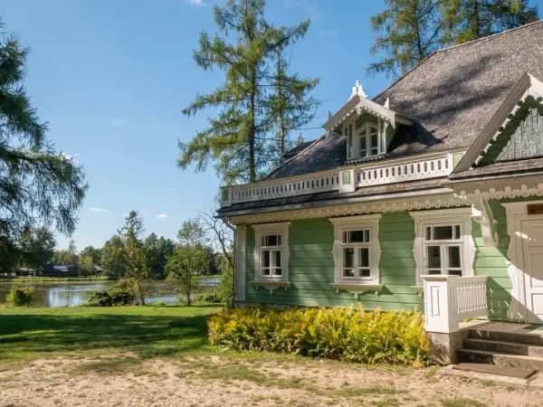 Zielony dworek z białymi zdobieniami, otoczony drzewami i jeziorem. Idealne miejsce na spokojny spacer i zapoznanie się z historią - białowieża plan zwiedzania.