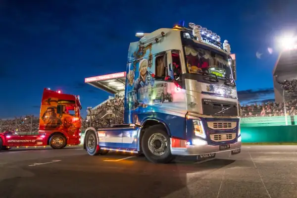 Deux camions décorés, dont un aux couleurs de Spiderman, défilent sur la piste du Mans devant une foule en délire.