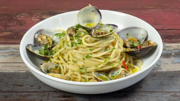 Spaghetti alle vongole, un piatto gustoso con vongole fresche e prezzemolo, pronto per essere gustato.