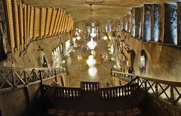 Wielka komora kopalni soli „Wieliczka” z kryształowymi żyrandolami i turystami. Opinie o tym miejscu są zachwycające.