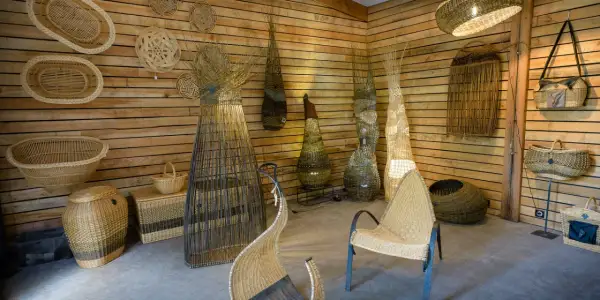 Atelier de vannerie. Des paniers, des luminaires et des sièges en osier, prêts à peindre de l'osier, décorent les murs en bois.
