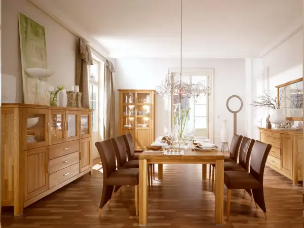 Elegancki salon w starym stylu aranżacje: drewniane meble, brązowe krzesła i stół nakryty do kolacji.